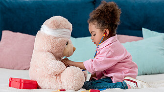 Ein kleines Mädchen spielt mit ihrem Teddybären Arzt.