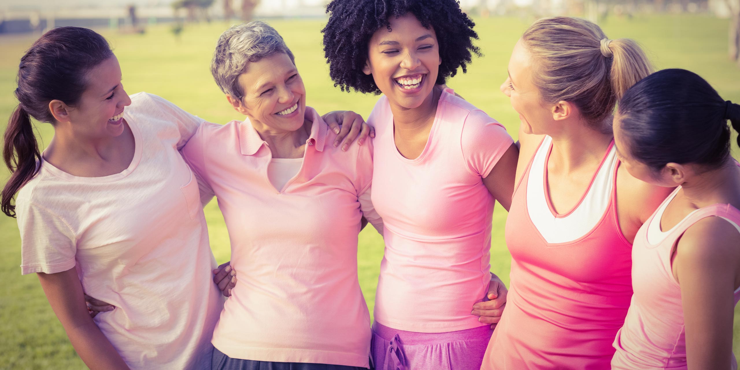 Gruppe lächelnder Frauen in rosa Trikots bzw. Shirts und violetten Sporthosen